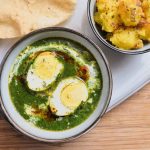 Palak Anda Curry, indisches Spinat-Curry mit Eiern. Daneben Jira Aloo und Papadums