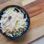 Coleslaw mit Spitzkohl in blauer Keramikschale auf Holzbrett